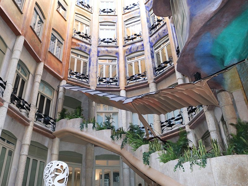 Interior view of Casa Milà ground floor showing the courtyard-facing facade, irregular circular layout, Barcelona