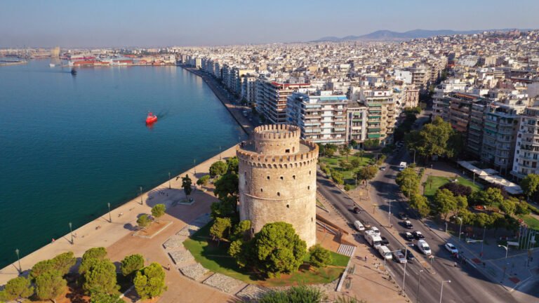 Aerial panoramic view of Thessaloniki showing coastline, dense urban grid, and waterfront