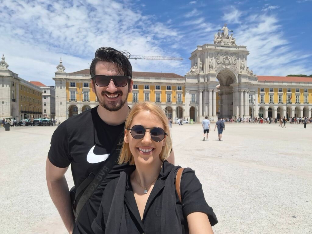 Group of travelers standing in Praça do Comércio, the main square in Lisbon with riverfront architecture in the background