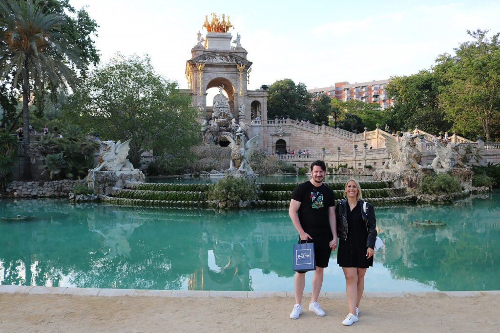 Two travelers standing in Parc de la Ciutadella surrounded by greenery, paths, and park scenery