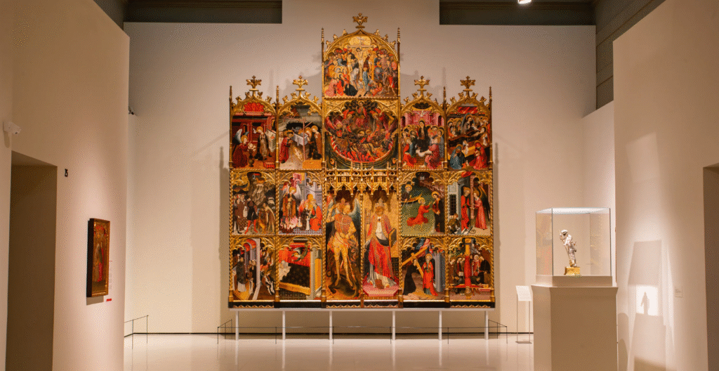 Interior exhibition hall of the National Art Museum of Catalonia showing artworks and religious frescoes displayed in a gallery space
