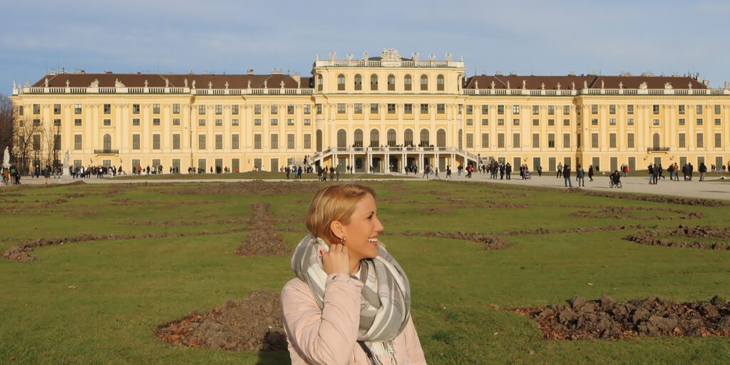 Traveler standing in front of the Schönbrunn Palace with baroque façade and gardens in the background