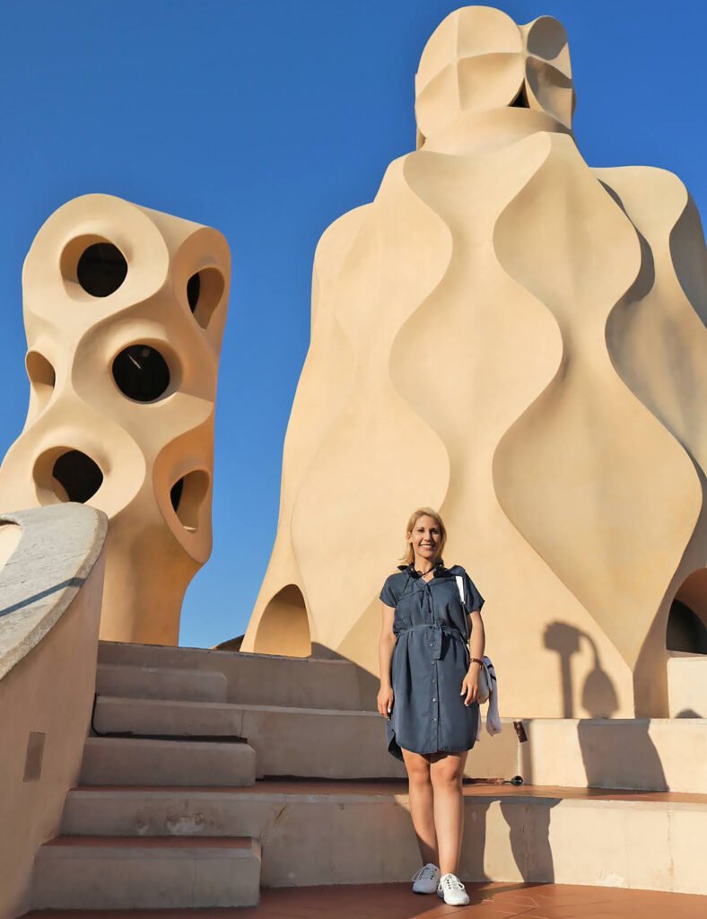 Traveler standing on the rooftop of Casa Milà surrounded by sculptural chimneys and rooftop architecture
