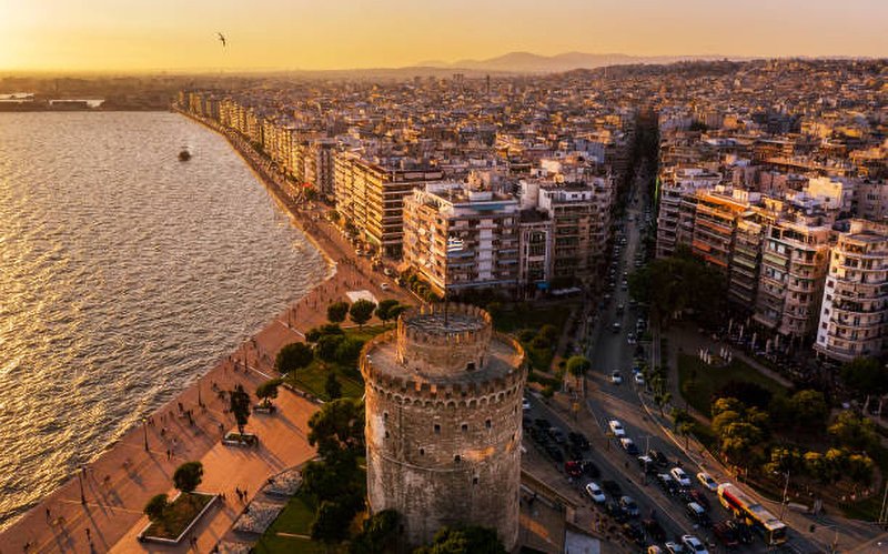 Aerial panoramic view of Thessaloniki showing coastline, dense urban grid, and waterfront