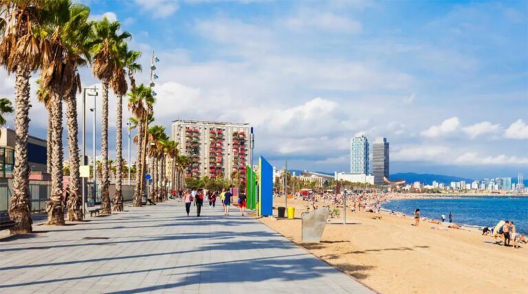 Sandy urban beach along the coastline of Barcelona with people relaxing and Mediterranean Sea in the background