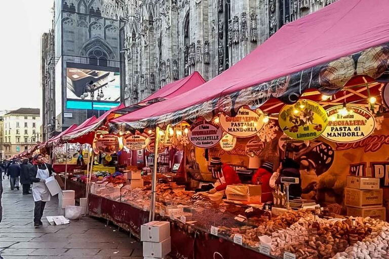 Christmas market at Piazza del Duomo in Milan, with festive stalls, decorations, and the cathedral in the background.