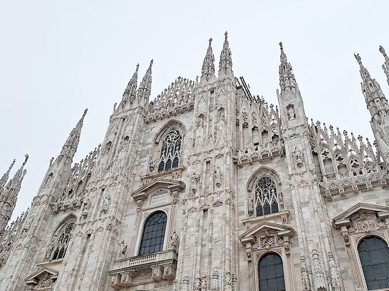Frontal view of Duomo di Milano in Milan, showcasing its Gothic facade with spires, statues, and ornate details.