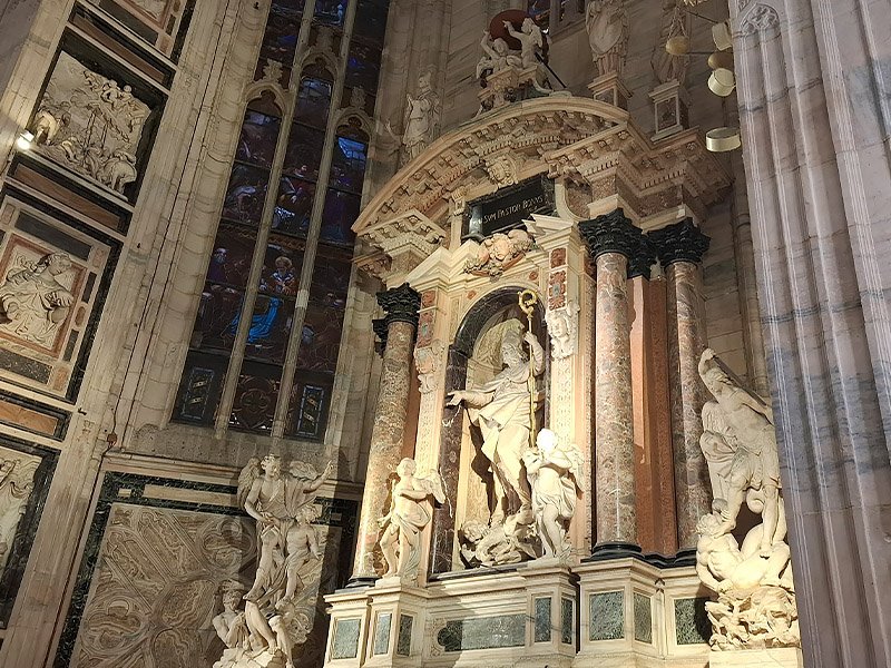 Interior of Duomo di Milano, Milan, showing sculptures and the cathedral’s crypt with Gothic architectural details.