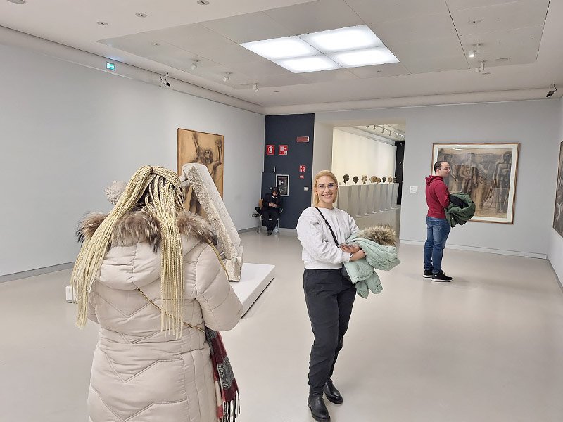 Visitors exploring an exhibition room inside Museo del Novecento in Milan, surrounded by modern artworks on display.