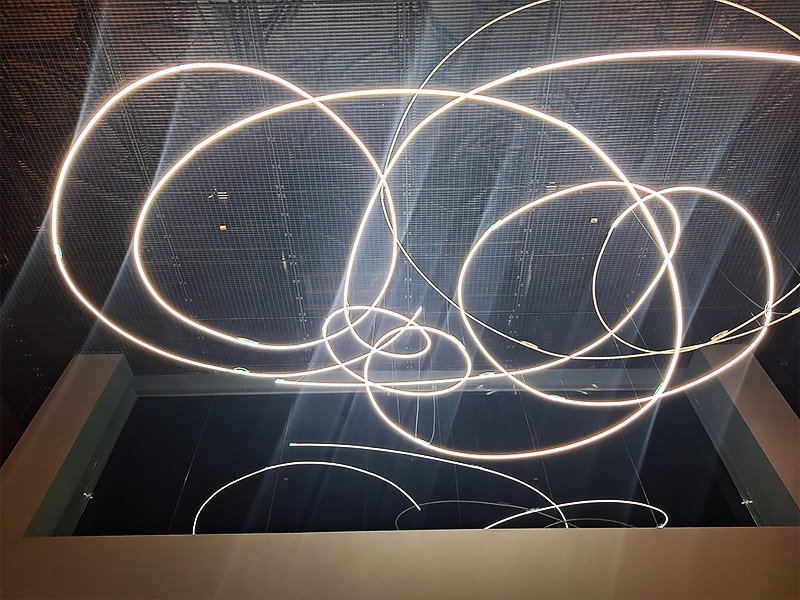 Ceiling with iconic lighting installation in the grand hall of Museo del Novecento in Milan, showcasing modern design and architectural detail.